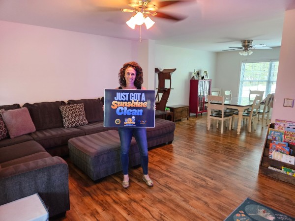 Allison holding a Just Got A Sunshine Clean sign