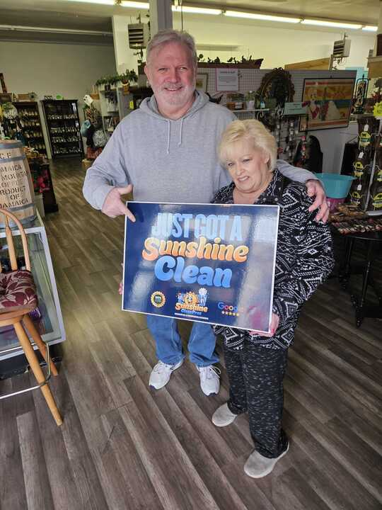 Tom and Beth holding a Just Got A Sunshine Clean sign